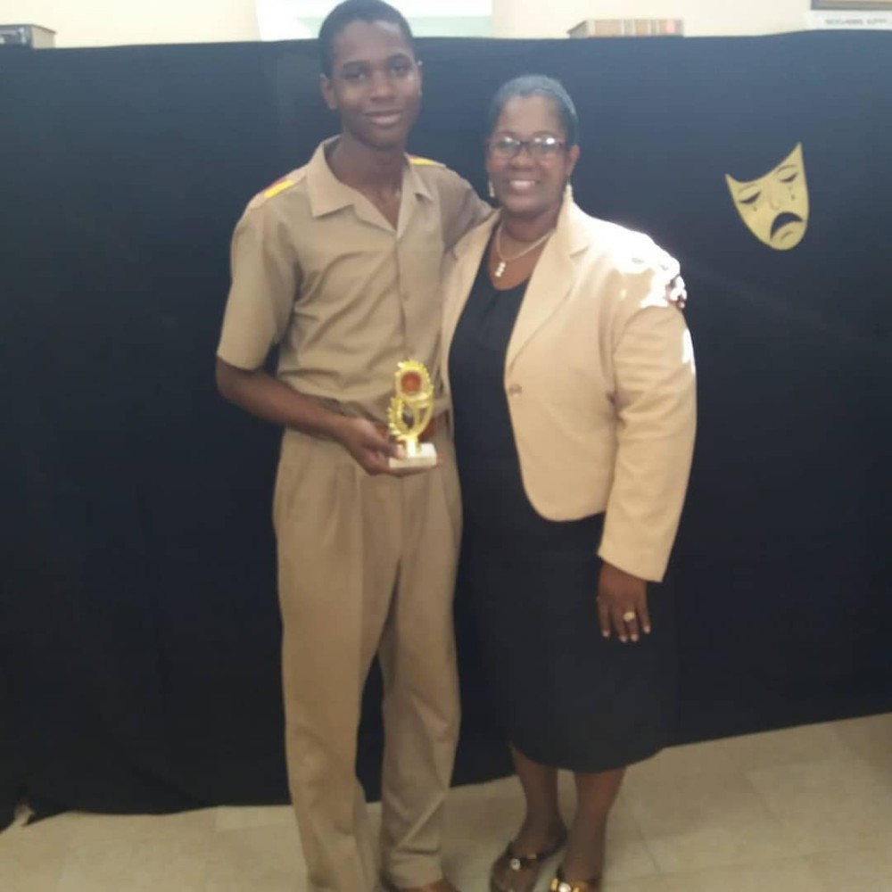 Velton Gooden Jr collecting his second Wolmer's Boys' Poetry Competition trophy with his mother