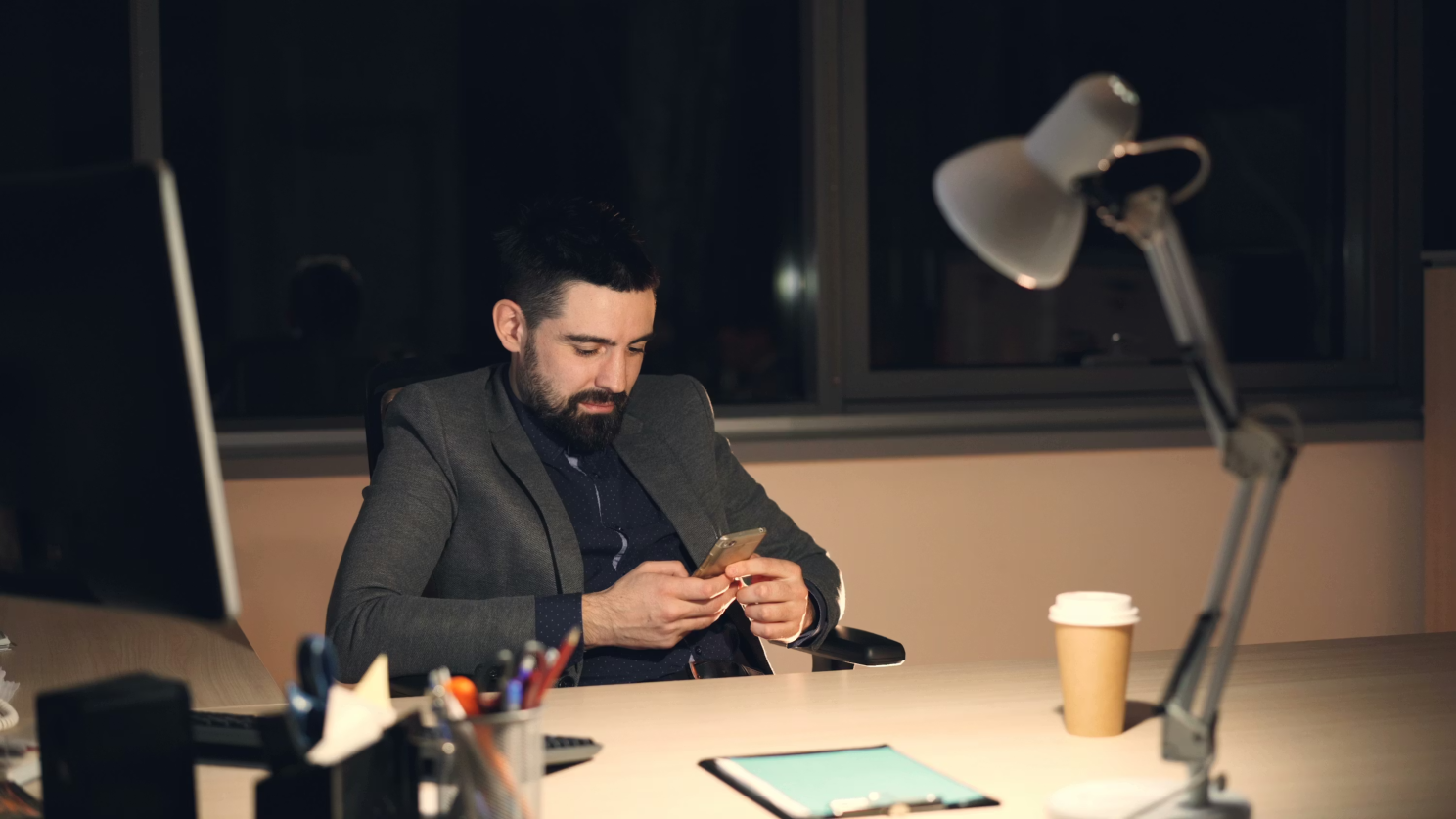Person looking at a phone at a desk at night