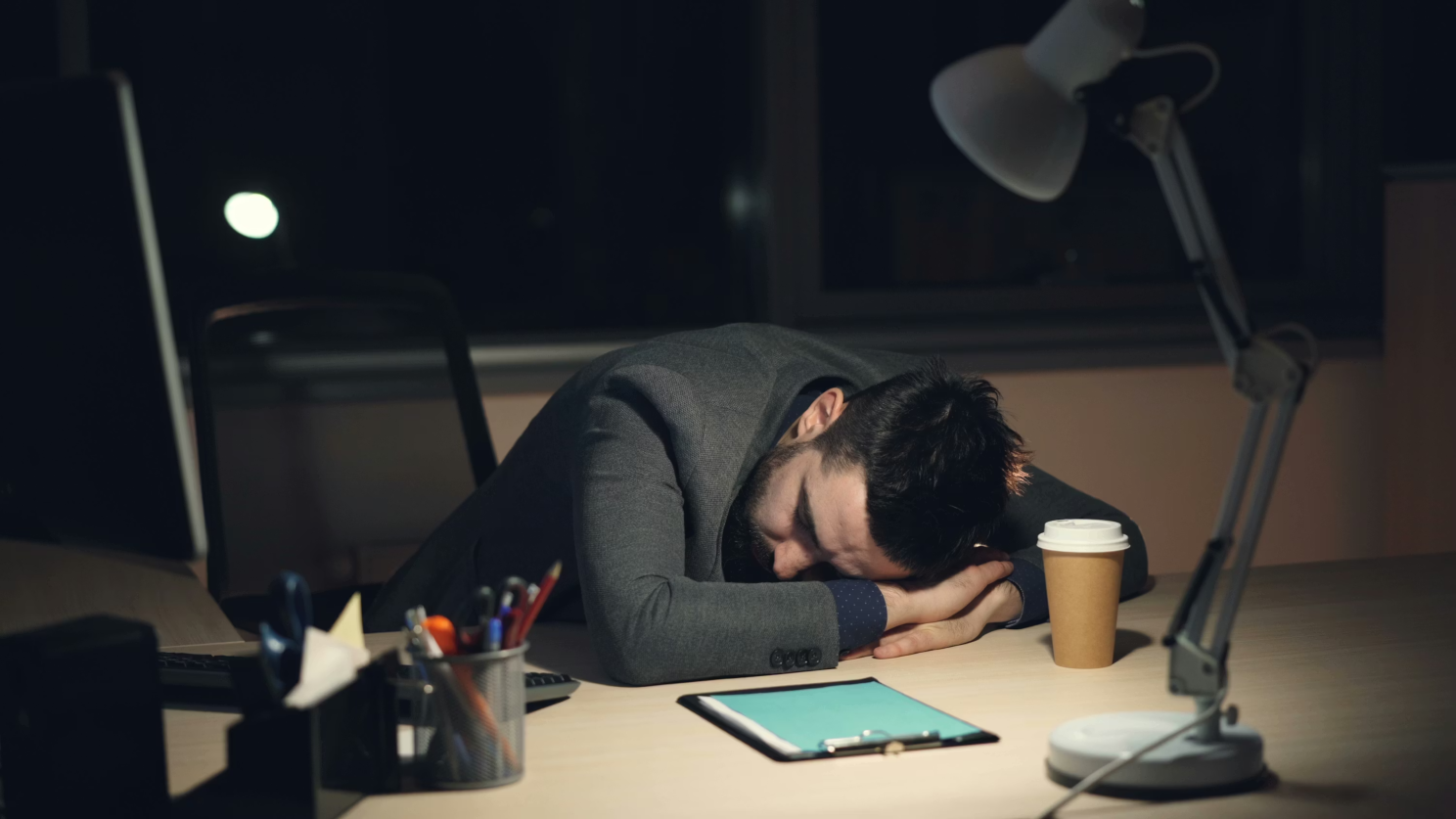 Person asleep at a desk at night