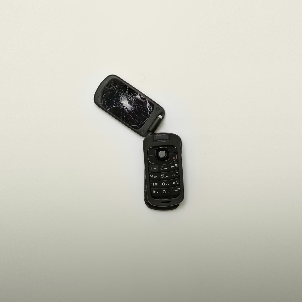 A broken flip phone with a cracked screen